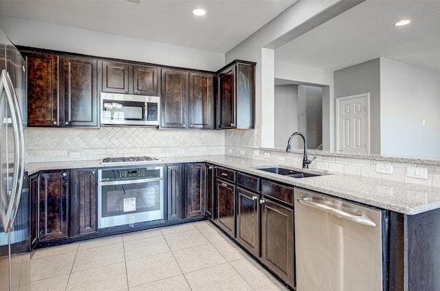 kitchen featuring light stone countertops, sink, stainless steel appliances, kitchen peninsula, and dark brown cabinets