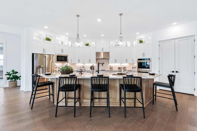 kitchen featuring a large island, white cabinetry, stainless steel appliances, and hanging light fixtures