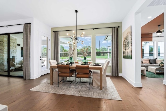 dining room with hardwood / wood-style floors, a healthy amount of sunlight, and ceiling fan with notable chandelier