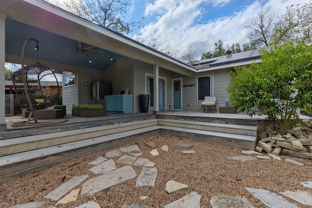 back of property with ceiling fan and solar panels