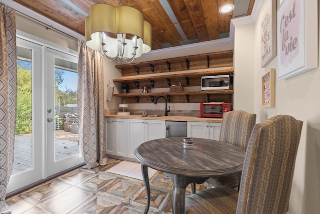 dining area featuring sink, crown molding, wood ceiling, french doors, and a chandelier