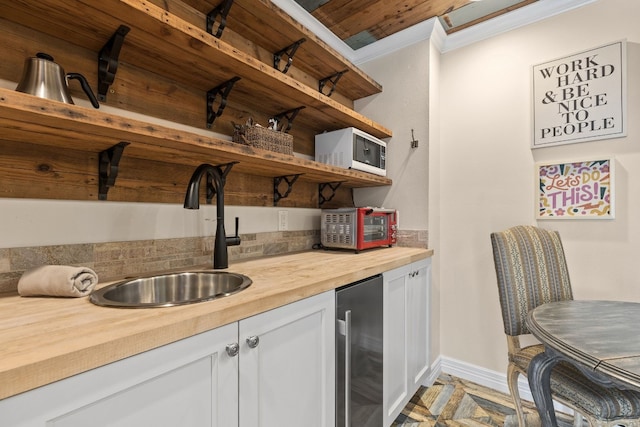 bar with white cabinets, wooden counters, wine cooler, sink, and crown molding