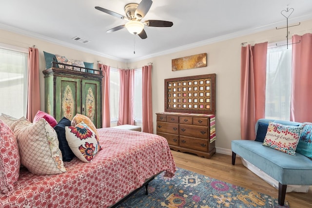 bedroom featuring ceiling fan, multiple windows, and ornamental molding