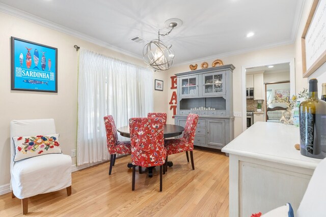 dining room featuring an inviting chandelier, ornamental molding, and light hardwood / wood-style flooring