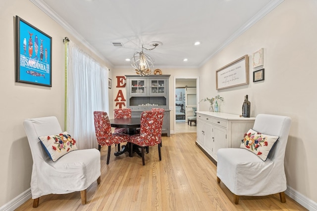 dining area with light wood-type flooring, a chandelier, and crown molding