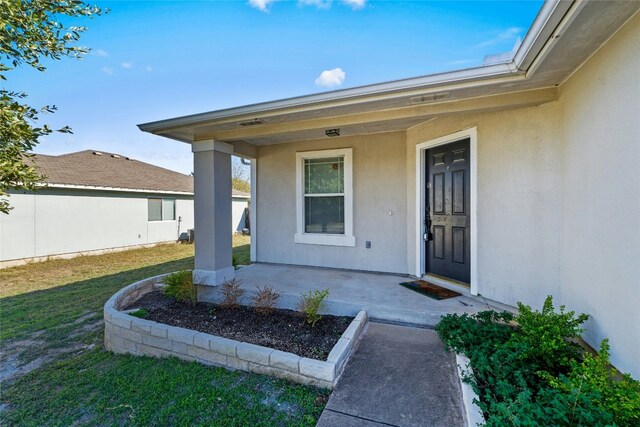 entrance to property featuring covered porch and a lawn