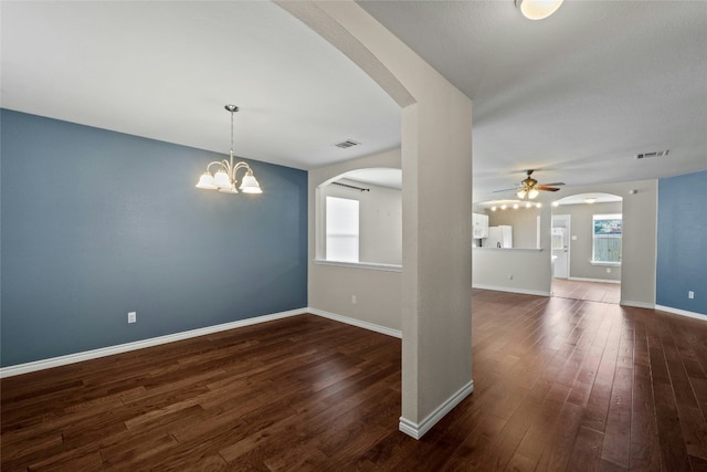 unfurnished room featuring ceiling fan with notable chandelier and dark wood-type flooring