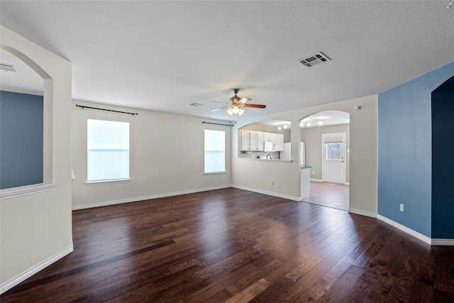 unfurnished living room with ceiling fan, dark hardwood / wood-style flooring, and a textured ceiling