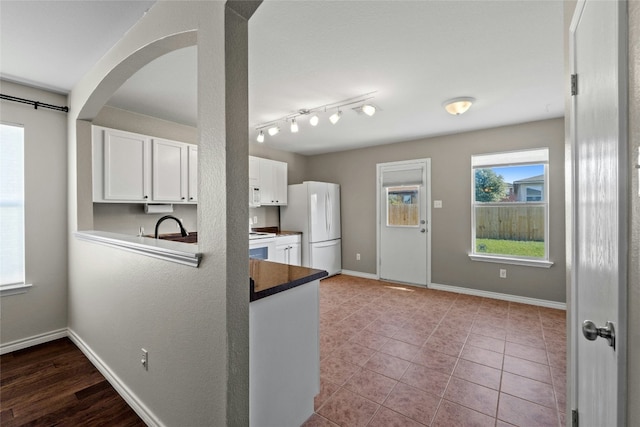 kitchen featuring white cabinetry, light tile patterned floors, track lighting, and white appliances