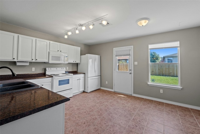 kitchen featuring sink, light tile patterned flooring, dark stone countertops, white appliances, and white cabinets