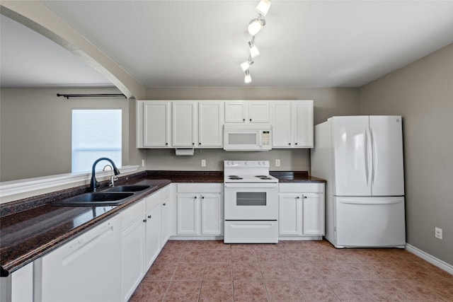 kitchen with dark stone counters, white appliances, sink, white cabinetry, and light tile patterned flooring