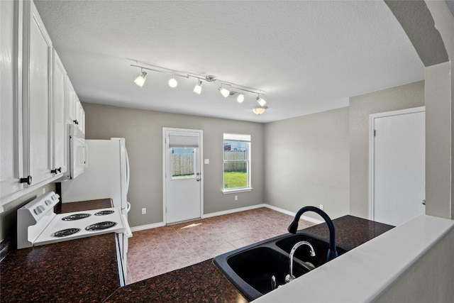 kitchen with sink, light tile patterned floors, a textured ceiling, white appliances, and white cabinets