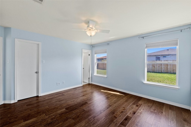 unfurnished room with plenty of natural light, ceiling fan, and dark wood-type flooring