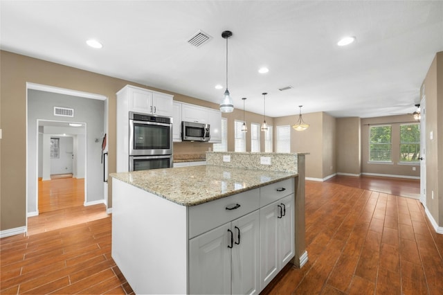 kitchen with white cabinetry, a kitchen island, wood-type flooring, and appliances with stainless steel finishes