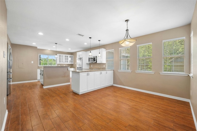 kitchen featuring pendant lighting, white cabinets, light hardwood / wood-style floors, appliances with stainless steel finishes, and a kitchen island