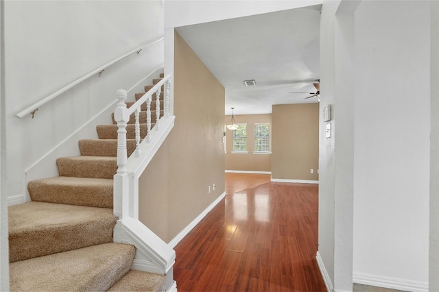 stairway with hardwood / wood-style floors and ceiling fan