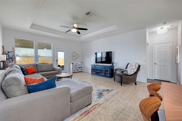 tiled living room featuring a raised ceiling and ceiling fan