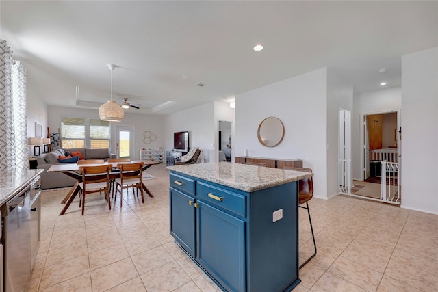 kitchen with ceiling fan, dishwasher, blue cabinets, a kitchen bar, and a kitchen island