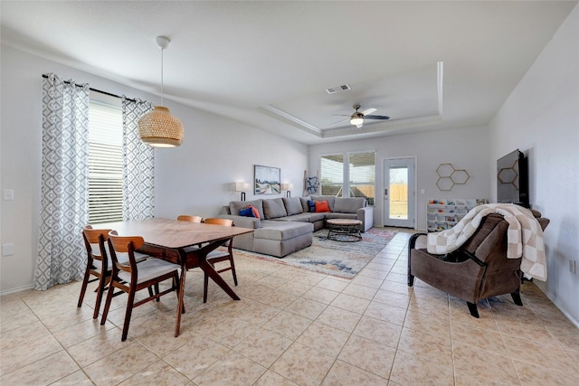 tiled living room featuring a tray ceiling and ceiling fan