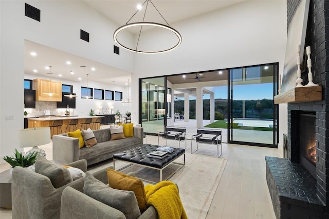 living room with a fireplace, a high ceiling, and light hardwood / wood-style floors