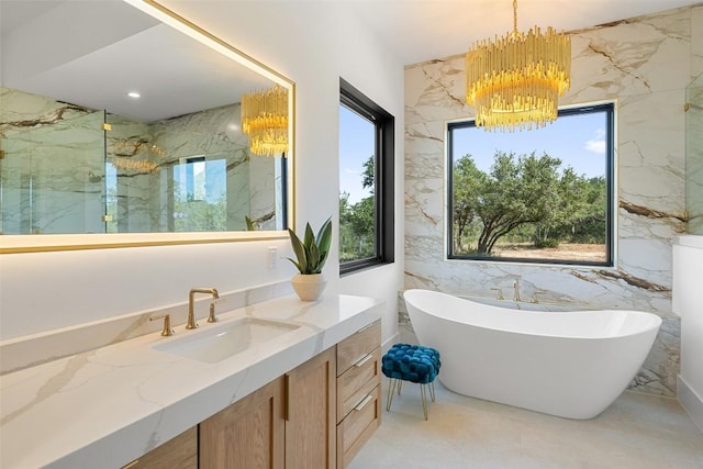 bathroom with plenty of natural light, tile walls, vanity, and an inviting chandelier