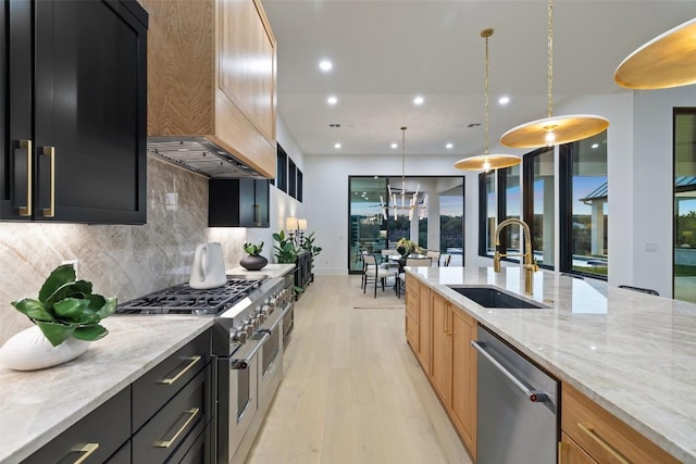 kitchen featuring light stone countertops, stainless steel appliances, sink, decorative light fixtures, and light hardwood / wood-style flooring