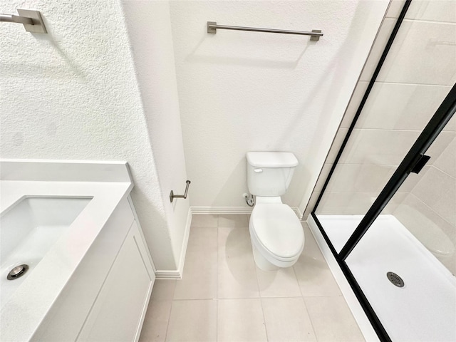 bathroom featuring tile patterned floors, vanity, a tile shower, and toilet