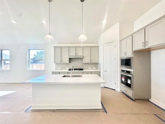 kitchen featuring gray cabinetry, hanging light fixtures, an island with sink, and appliances with stainless steel finishes