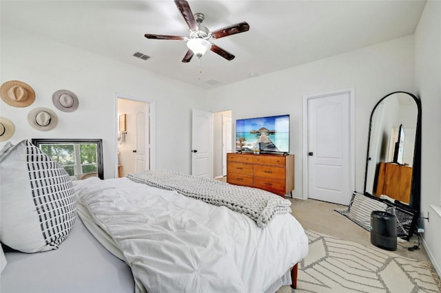 bedroom with light carpet, ensuite bathroom, and ceiling fan