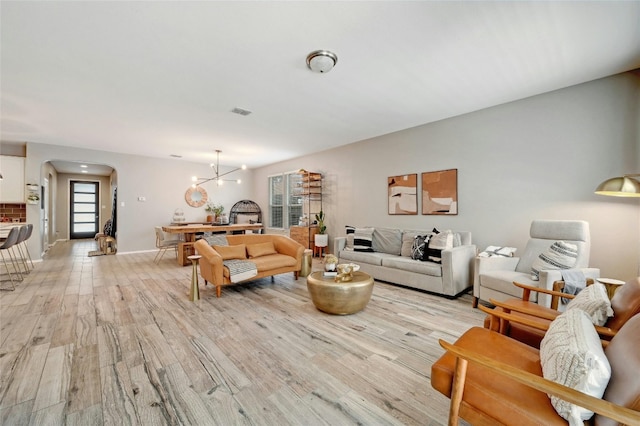 living room featuring light wood-type flooring and an inviting chandelier