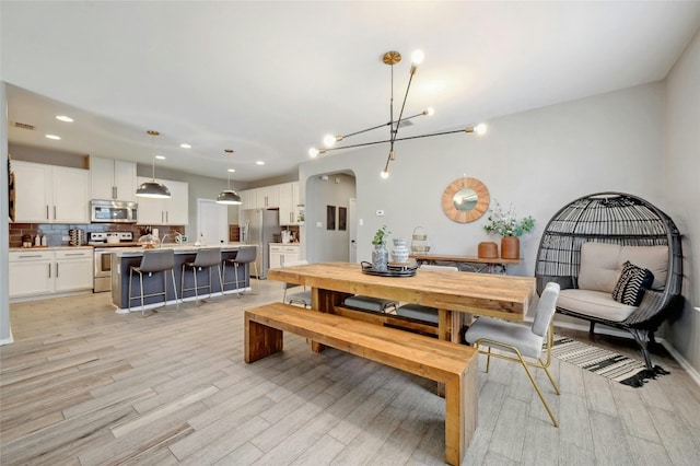 dining space featuring light wood-type flooring, a notable chandelier, and sink