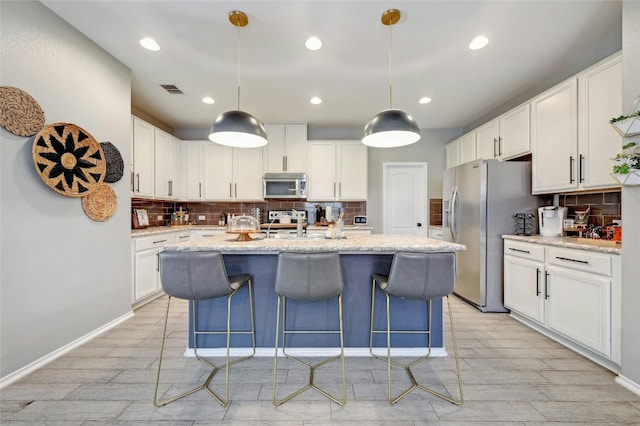 kitchen featuring white cabinets, decorative light fixtures, and stainless steel appliances