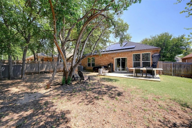 rear view of property with a lawn, a patio area, and solar panels