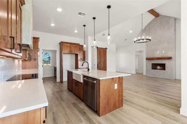 kitchen with a center island with sink, black electric stovetop, sink, stainless steel dishwasher, and decorative light fixtures