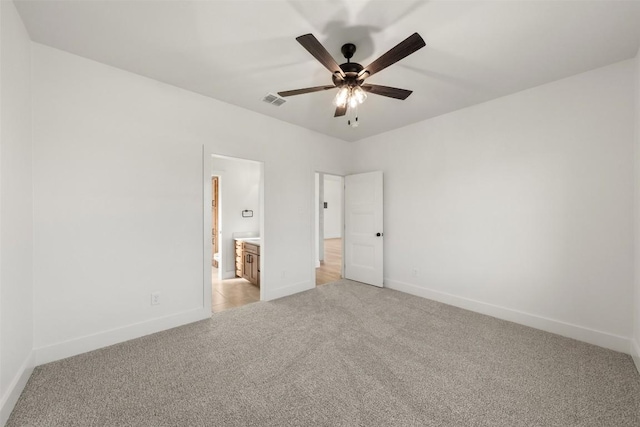 unfurnished bedroom with ceiling fan, light colored carpet, and ensuite bathroom