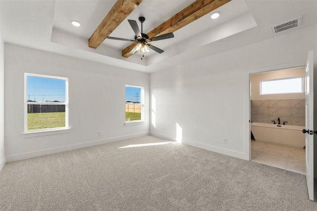 unfurnished bedroom featuring ceiling fan, light colored carpet, ensuite bathroom, and multiple windows