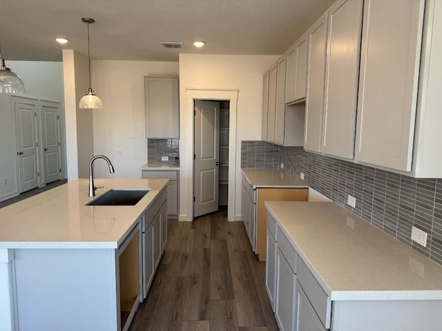 kitchen with pendant lighting, sink, white cabinetry, dark hardwood / wood-style floors, and an island with sink