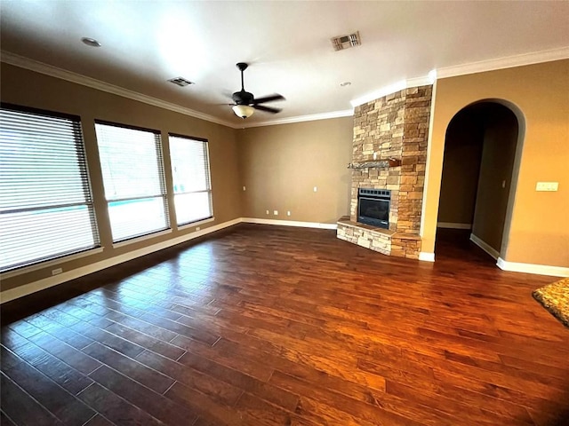 unfurnished living room featuring ornamental molding, a stone fireplace, ceiling fan, and dark wood-type flooring