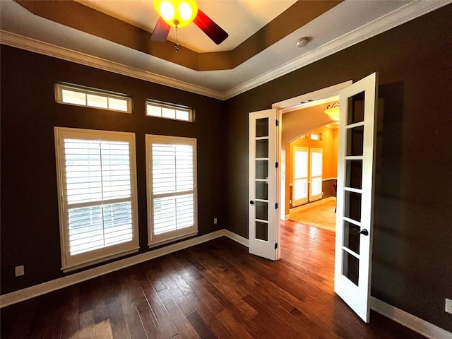 spare room featuring a raised ceiling, ceiling fan, french doors, and dark wood-type flooring