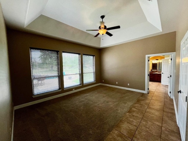 empty room featuring carpet flooring, ceiling fan, and a tray ceiling