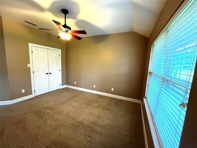 unfurnished bedroom featuring ceiling fan, dark carpet, lofted ceiling, and a closet