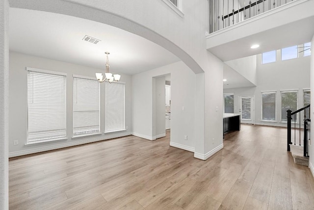 interior space with a towering ceiling, a chandelier, and light wood-type flooring