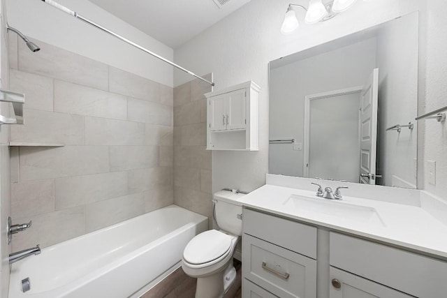 full bathroom featuring hardwood / wood-style floors, tiled shower / bath combo, toilet, and vanity