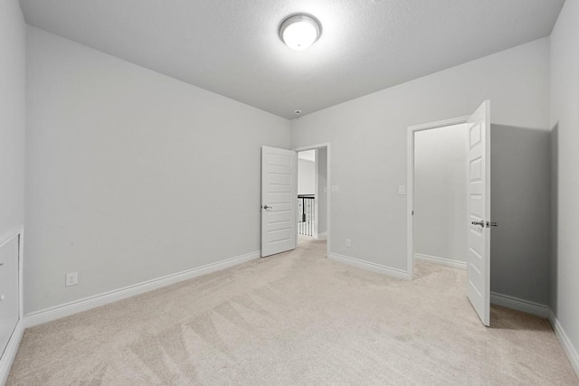 unfurnished bedroom with a textured ceiling and light colored carpet