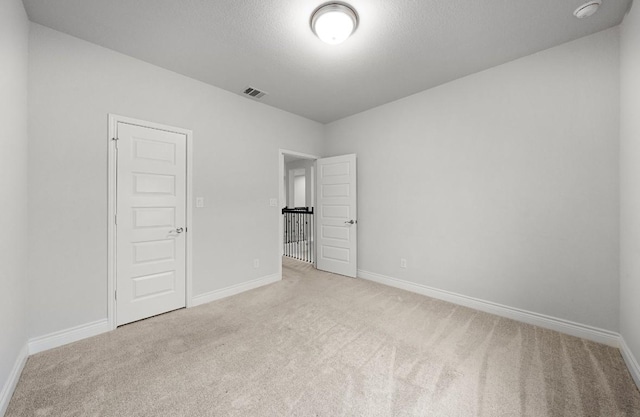 unfurnished bedroom featuring a closet, light colored carpet, and a textured ceiling