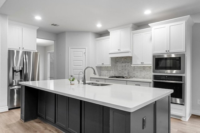 kitchen with a center island with sink, white cabinets, and stainless steel appliances