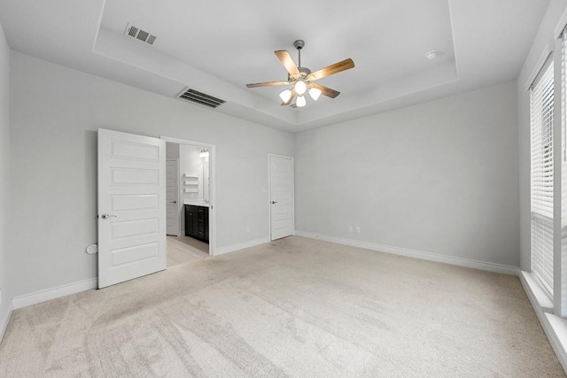 unfurnished bedroom featuring ceiling fan, a raised ceiling, and ensuite bathroom