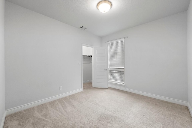 unfurnished bedroom featuring carpet flooring, a spacious closet, and a closet