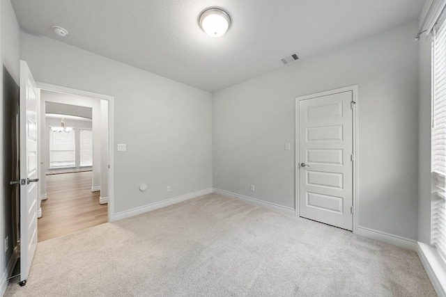 carpeted spare room featuring plenty of natural light and a notable chandelier