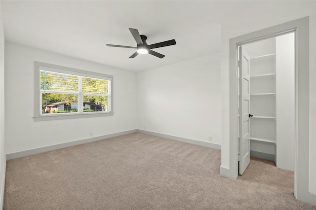 unfurnished bedroom featuring a walk in closet, ceiling fan, light carpet, and a closet